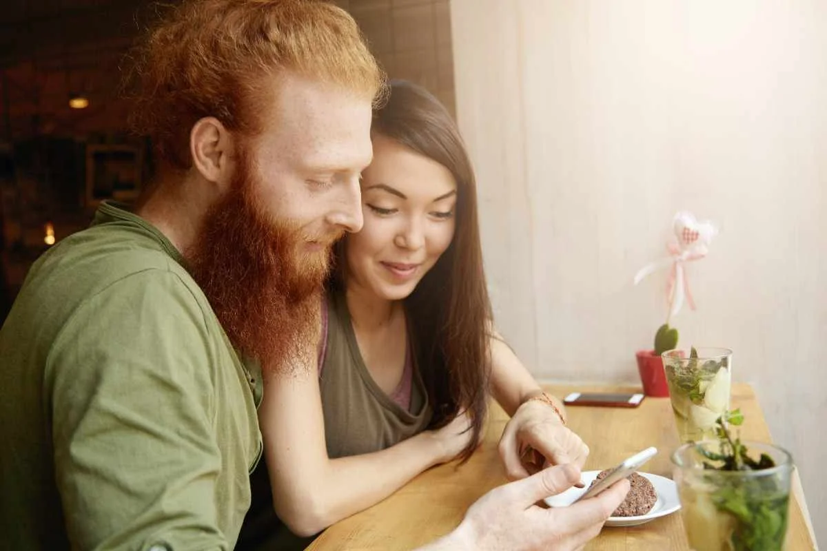 Smiling couple looking at a phone while chatting, enjoying flirty conversation together